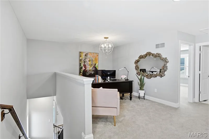 Open floor area featuring neutral carpeting, a spherical chandelier, and architectural half-wall railing — 17028 Fire Glow Drive, Wildwood, MO 63011