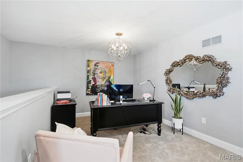 Orbital-style chandelier with metallic finish, neutral carpeting, and solid-toned wall surfaces — 17028 Fire Glow Drive, Wildwood, MO 63011