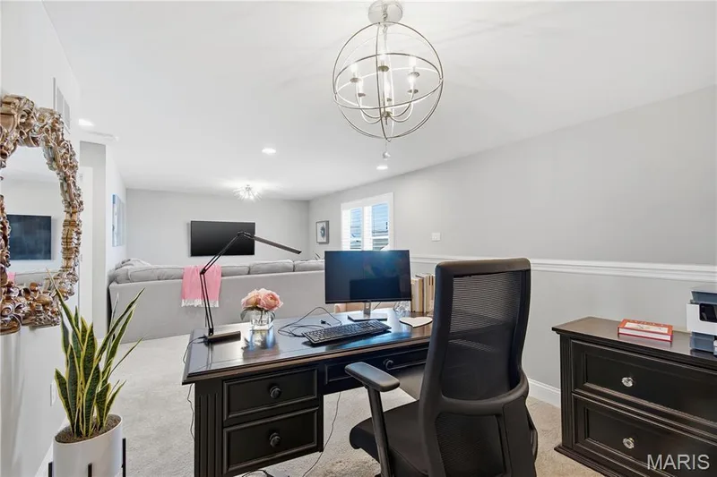 Open-concept interior featuring neutral wall tones, mid-height wainscoting, carpeted flooring, recessed lighting, and a spherical metal chandelier — 17028 Fire Glow Drive, Wildwood, MO 63011