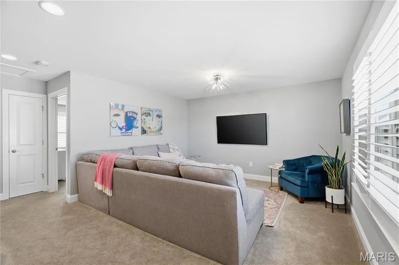 Neutral-toned interior space featuring recessed lighting, a modern starburst-style ceiling fixture, wall-to-wall carpeting, and white horizontal window blinds — 17028 Fire Glow Drive, Wildwood, MO 63011