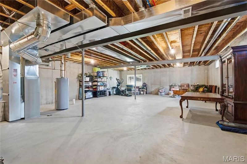Unfinished lower level featuring concrete flooring, exposed wood ceiling joists, steel support columns, and concrete foundation walls — 17028 Fire Glow Drive, Wildwood, MO 63011