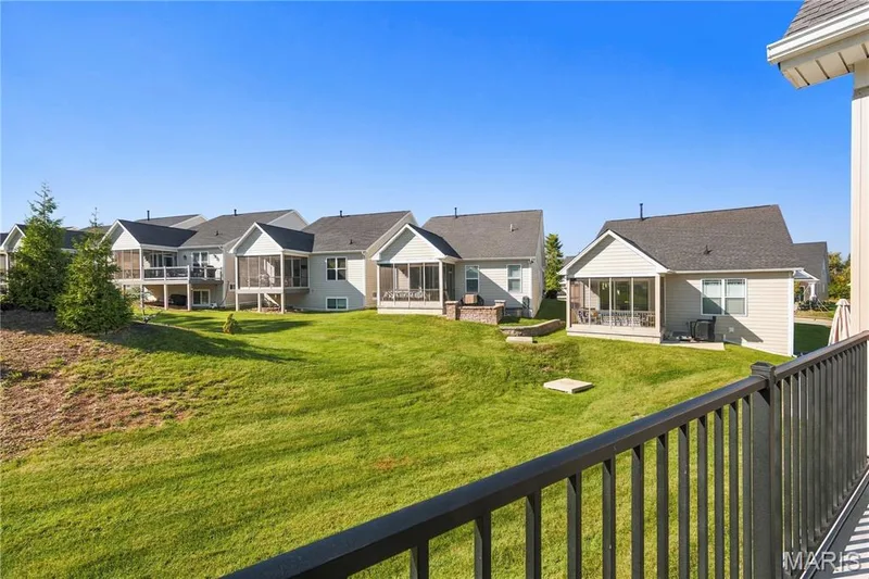 Rear exterior featuring screened-in porches, elevated decks with railings, stone-faced retaining walls, and expansive green space — 17028 Fire Glow Drive, Wildwood, MO 63011