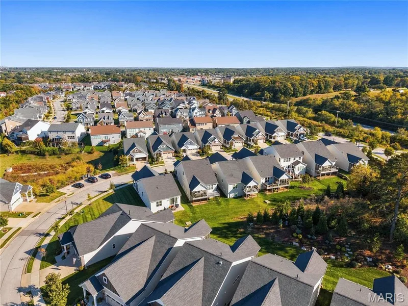 Aerial perspective of a residential neighborhood featuring multi-level dwellings with composite shingle roofing, cul-de-sac infrastructure, manicured lawns, and mature perimeter trees — 17028 Fire Glow Drive, Wildwood, MO 63011