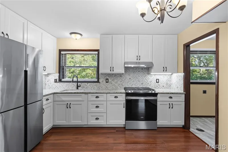Kitchen is newly updated with stunning granite countertops, stylish marble backsplash, stainless steel appliances, 42" custom cabinetry with under-cabinet lighting, farmhouse sink & newly installed fixtures! — 15 Bridlewood Drive, Lake St. Louis, MO 63367