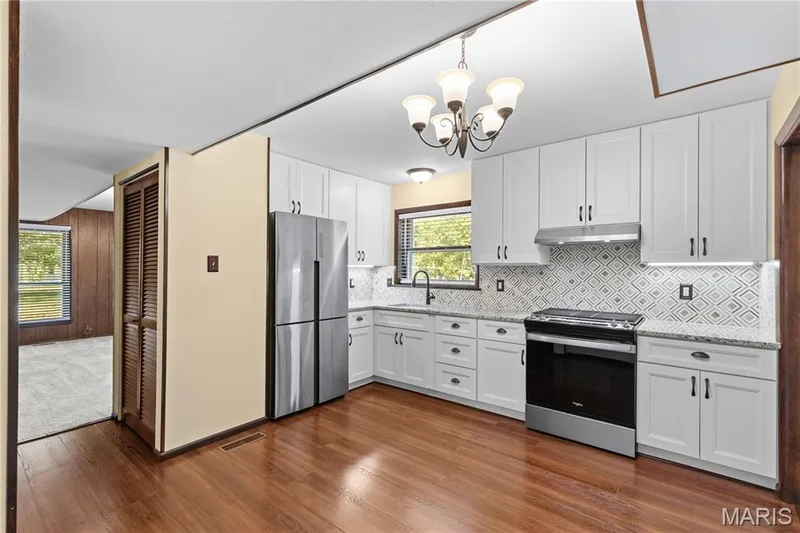 Kitchen is newly updated with stunning granite countertops, stylish marble backsplash, stainless steel appliances, 42" custom cabinetry with under-cabinet lighting, farmhouse sink & newly installed fixtures! — 15 Bridlewood Drive, Lake St. Louis, MO 63367