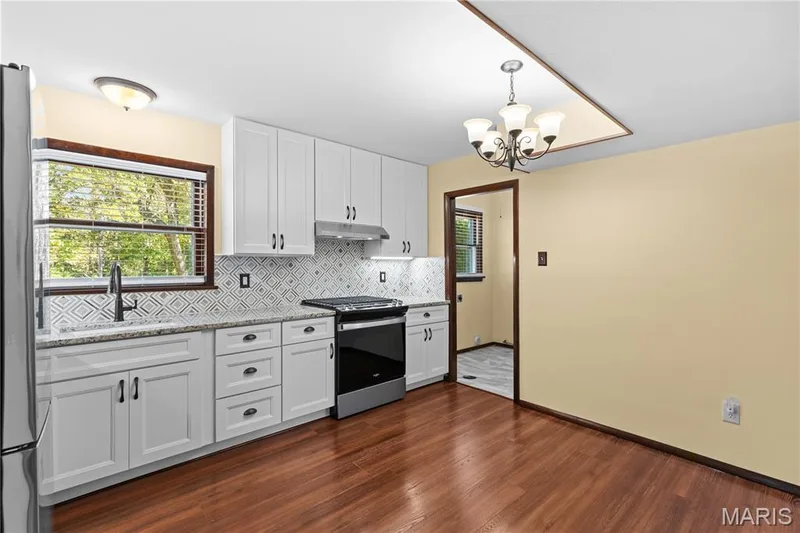 Kitchen is newly updated with stunning granite countertops, stylish marble backsplash, stainless steel appliances, 42" custom cabinetry with under-cabinet lighting, farmhouse sink & newly installed fixtures! — 15 Bridlewood Drive, Lake St. Louis, MO 63367