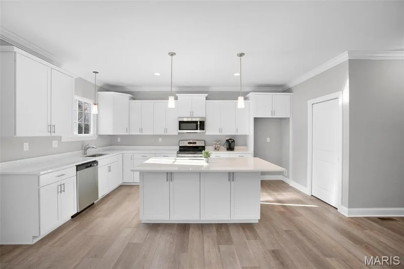 Standard kitchen with staggered cabinets, and large island with accessible cabinets on both sides. (Photo of previously built Sycamore - upgrades may be shown) — Sycamore-Ests @ Schaper Farms, Foristell, MO 63348