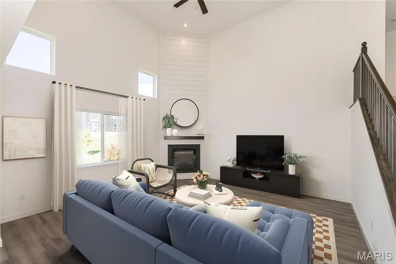 Living room featuring a towering ceiling, a fireplace, dark wood finished floors, a ceiling fan, and stairs — 717 Southerland Drive, O'Fallon, MO 63368