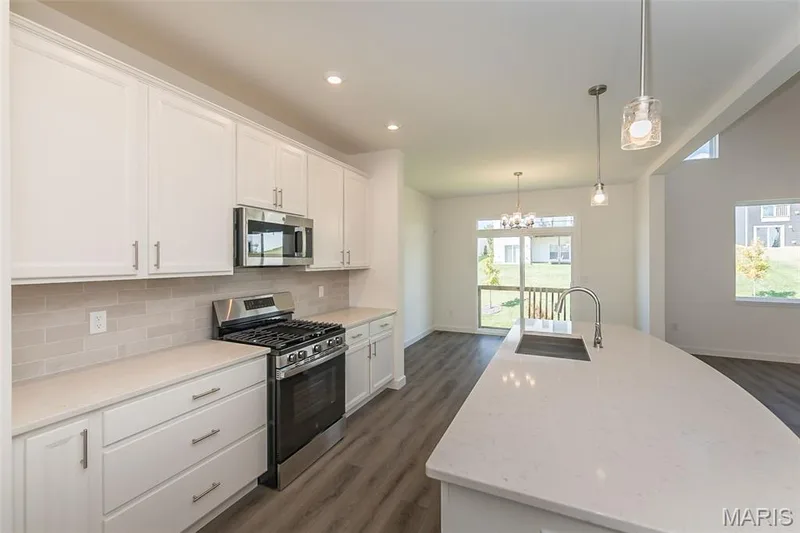 Kitchen with stainless steel appliances, decorative light fixtures, backsplash, white cabinets, and recessed lighting — 717 Southerland Drive, O'Fallon, MO 63368