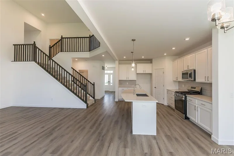 Kitchen with stainless steel appliances, pendant lighting, an island with sink, white cabinetry, and light wood-type flooring — 717 Southerland Drive, O'Fallon, MO 63368