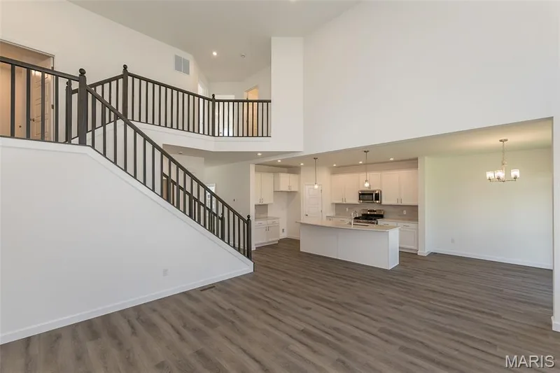 Unfurnished living room with recessed lighting, dark wood-style floors, stairs, and a chandelier — 717 Southerland Drive, O'Fallon, MO 63368