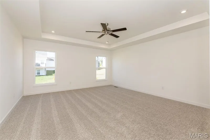 Unfurnished room with a tray ceiling, light colored carpet, recessed lighting, and ceiling fan — 717 Southerland Drive, O'Fallon, MO 63368