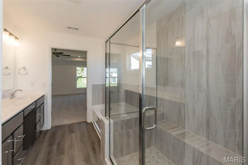 Full bath featuring double vanity, dark wood-style flooring, a shower stall, and a bath — 717 Southerland Drive, O'Fallon, MO 63368