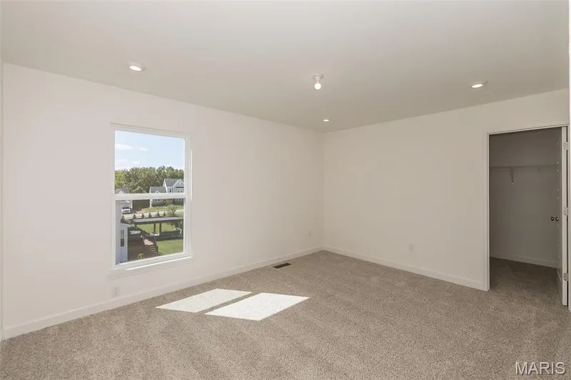 Unfurnished bedroom featuring a walk in closet, light carpet, and recessed lighting — 717 Southerland Drive, O'Fallon, MO 63368