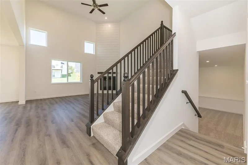 Stairway featuring wood finished floors, ceiling fan, and a high ceiling — 717 Southerland Drive, O'Fallon, MO 63368