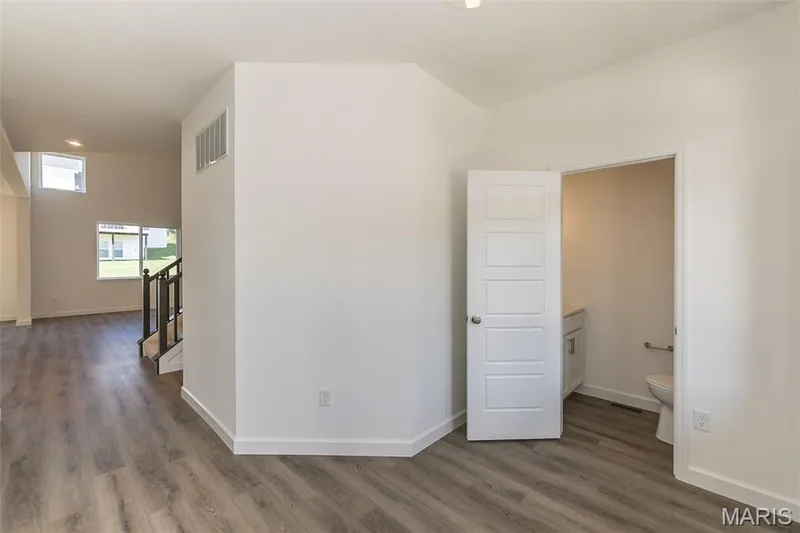 Unfurnished room featuring dark wood-type flooring and stairway — 717 Southerland Drive, O'Fallon, MO 63368